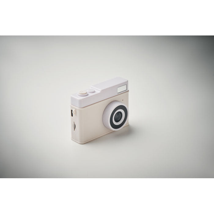 Small camera with a white top and beige body on a gray background