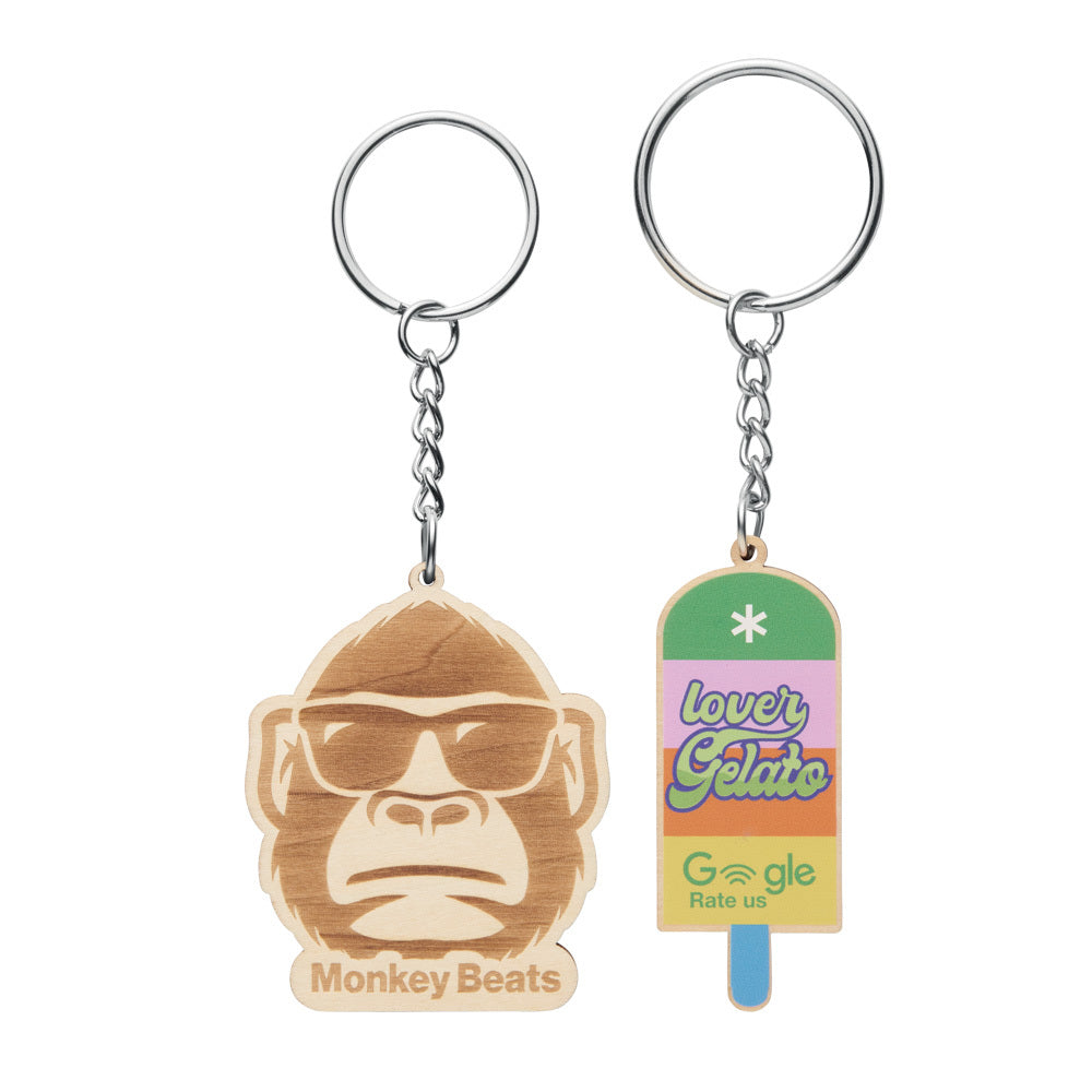 Two keychains, one with a monkey face design and the other resembling a popsicle with colorful text, on a white background.