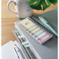 Notebook with colorful sticky notes, pen, and mug on a wooden surface