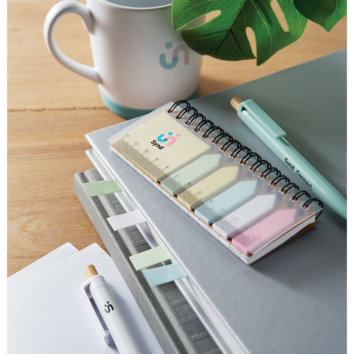 Notebook with colorful sticky notes, pen, and mug on a wooden surface