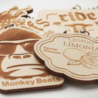 Wooden product tags with engraved designs and text on a white background