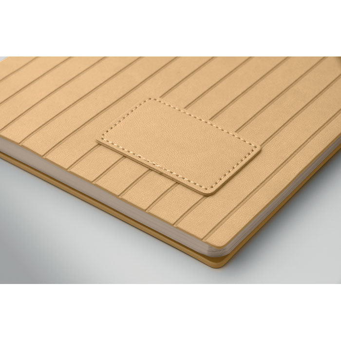 Beige leather-bound notebook with a textured cover on a light gray background